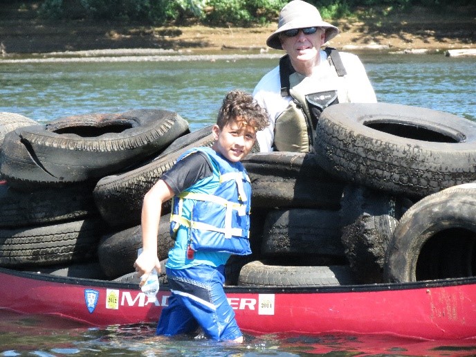 Father and son clearing creek of tires